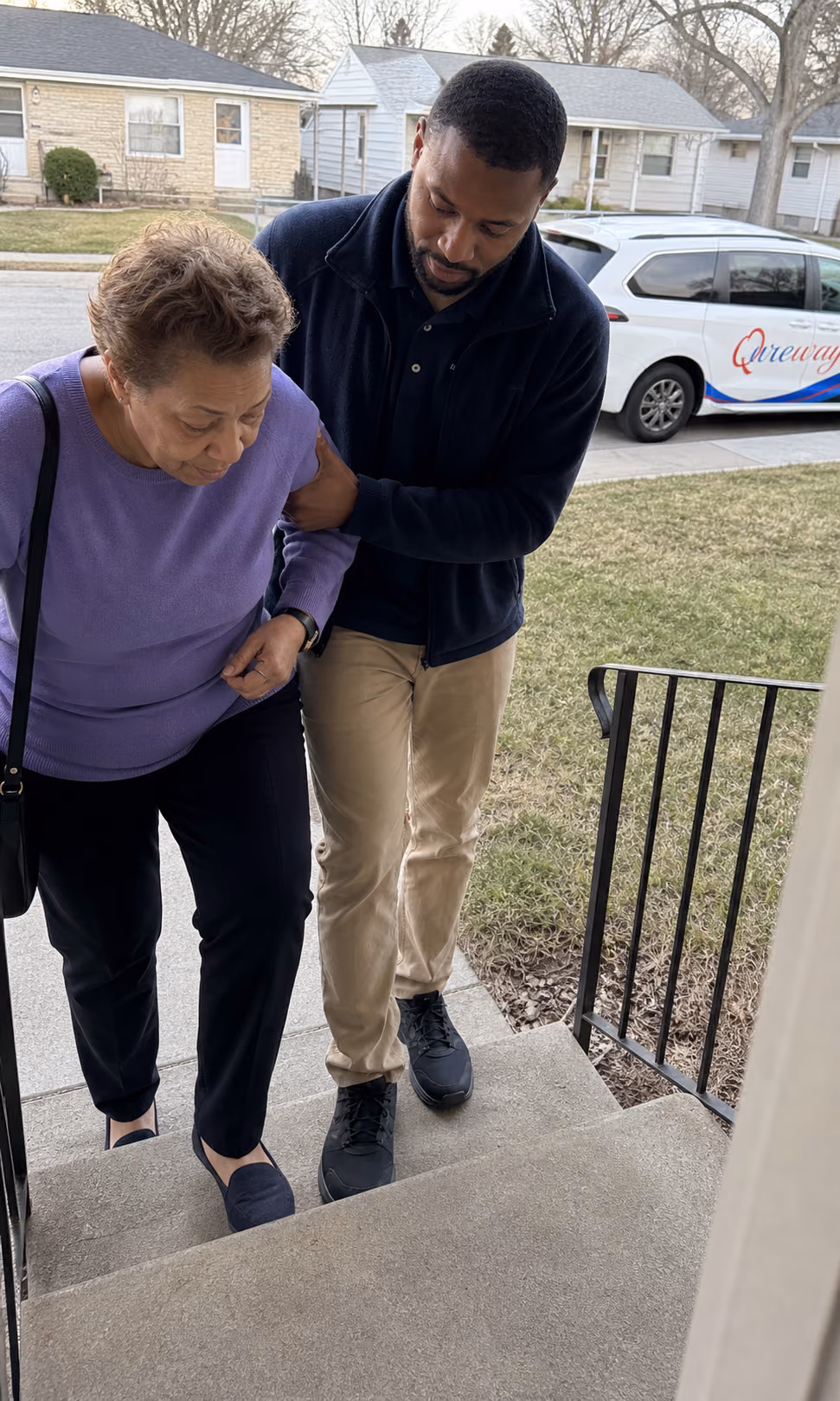 A Qureway driver offering a steady arm to a rider at her front steps