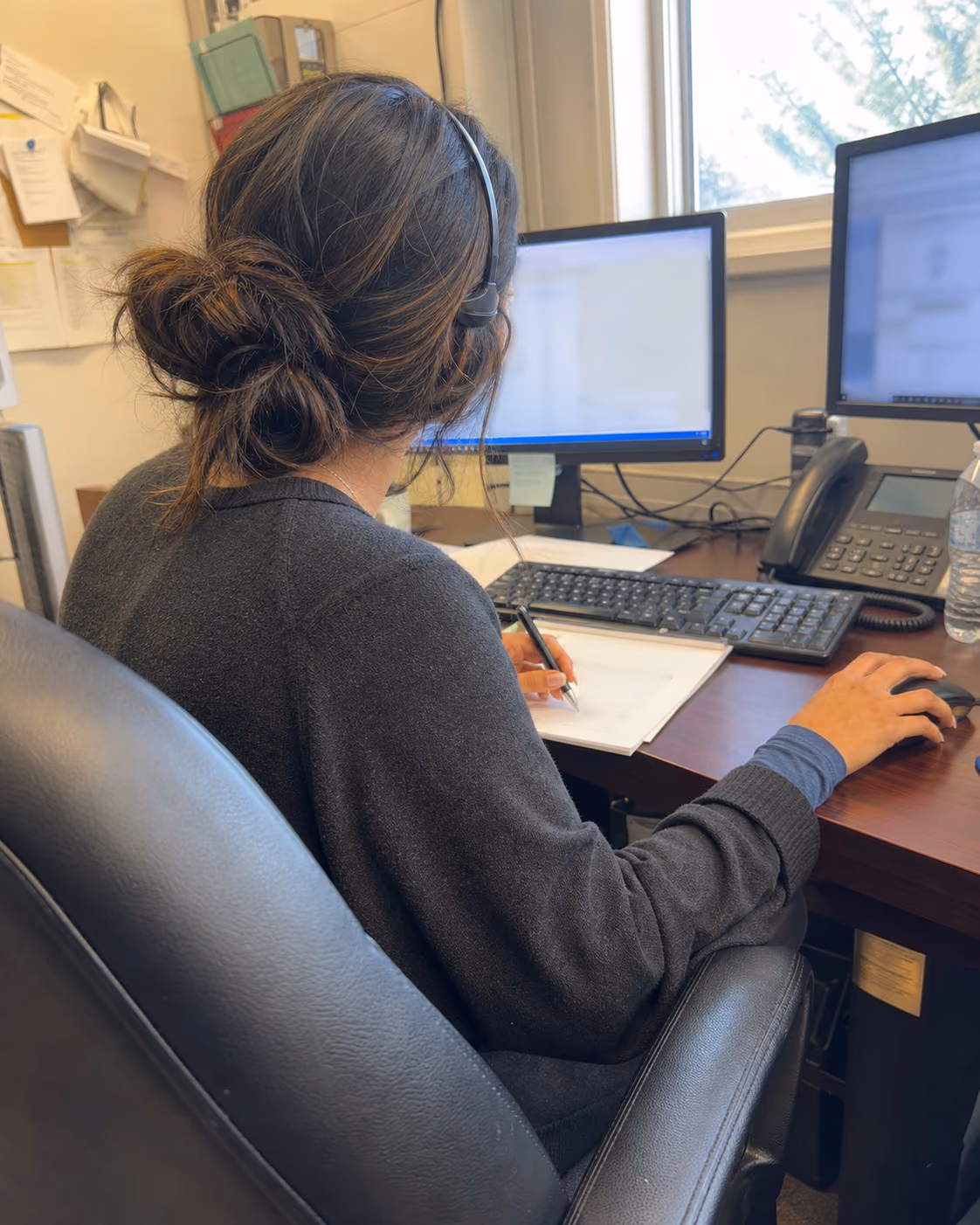 A dispatcher working at her desk while arranging a rider's trip