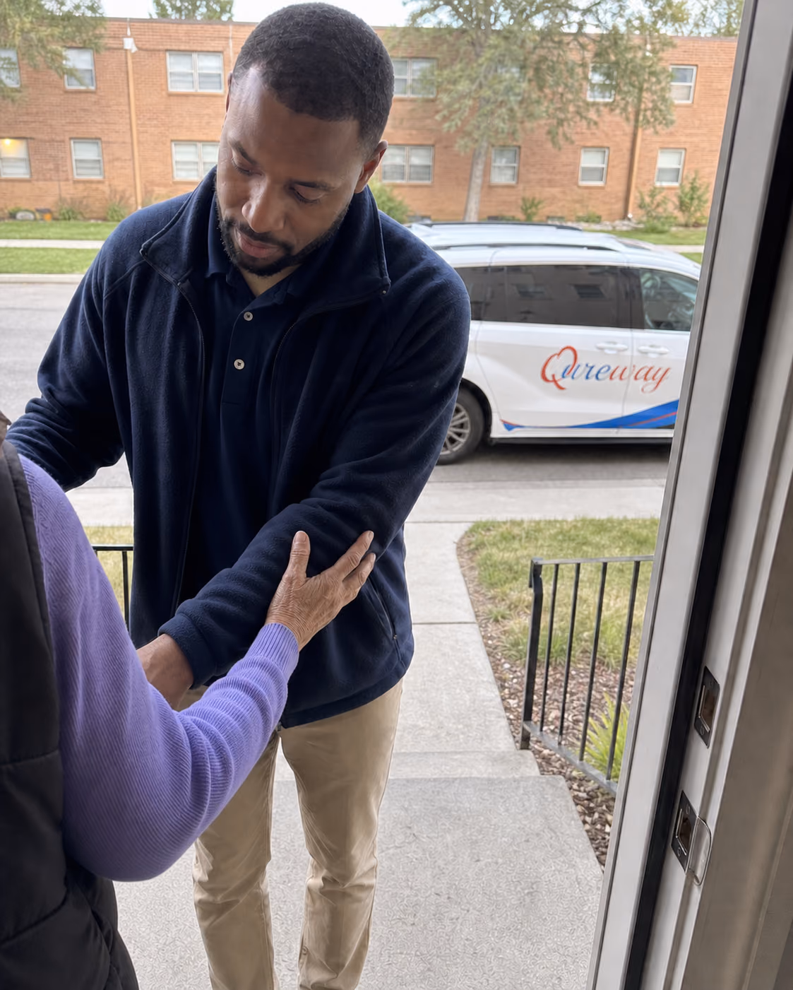 A Qureway driver arriving at a rider's front door and offering a steady arm
