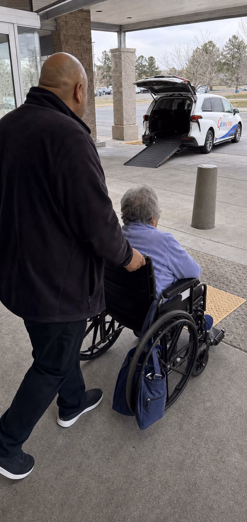 A Qureway driver preparing the rear wheelchair ramp outside a hospital discharge entrance